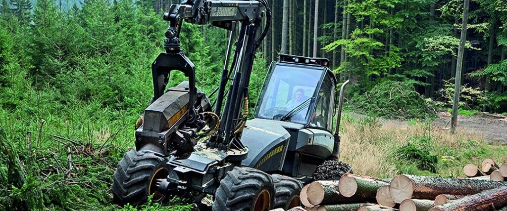 Kabinenverglasung aus hartbeschichtetem Polycarbonat im Harvester, die Bäume in einem grünen Wald bewegt.